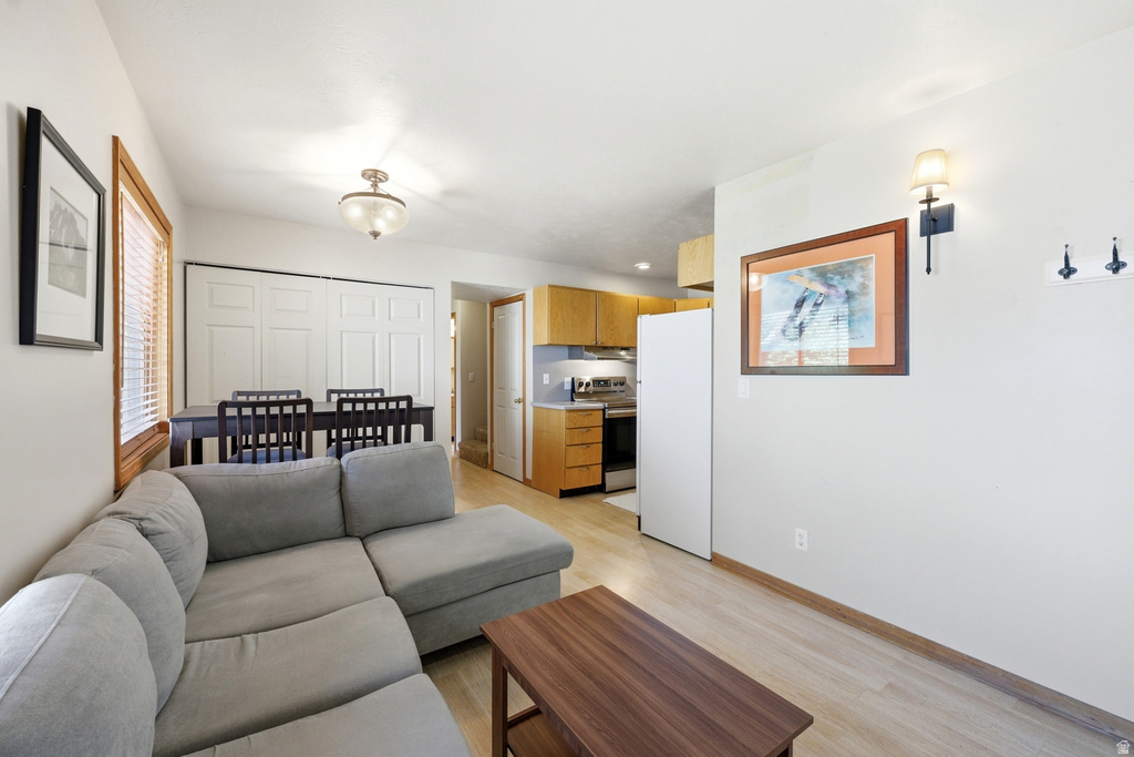 Open-concept living space featuring wood-finish flooring, a dining area with a chandelier, and a kitchen with warm-toned cabinetry