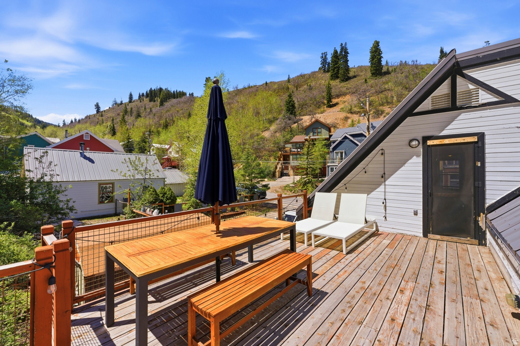 Exterior wood deck featuring a wire mesh railing, string lighting, and a sloped roofline