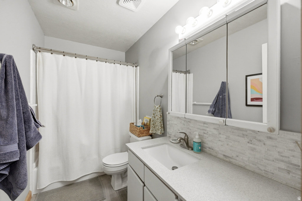 Bathroom featuring a vanity with an integrated sink, a light-colored countertop, and a tiled backsplash