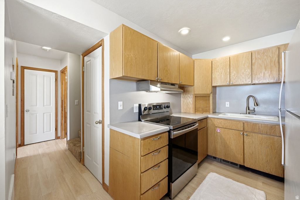 Kitchen featuring light wood-finish cabinetry, light countertops, stainless steel appliances, and a stainless steel sink with a gooseneck faucet