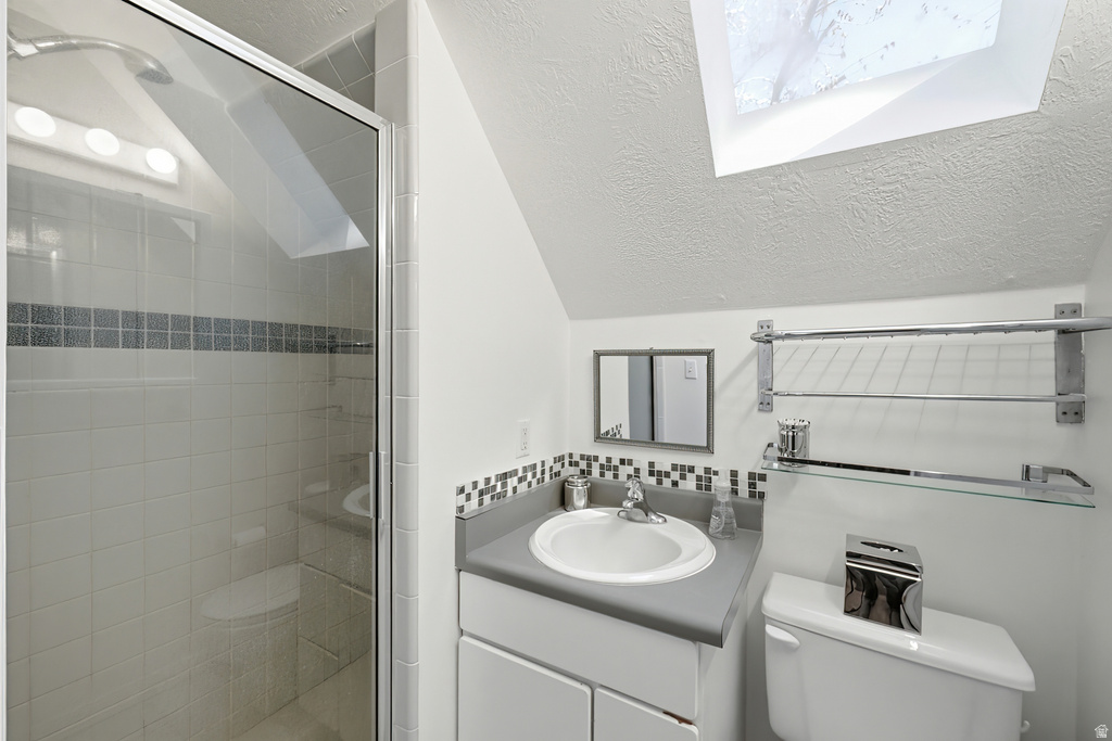 Bathroom featuring a glass-enclosed shower, white tile surround with decorative accent band, and a vanity with an integrated sink