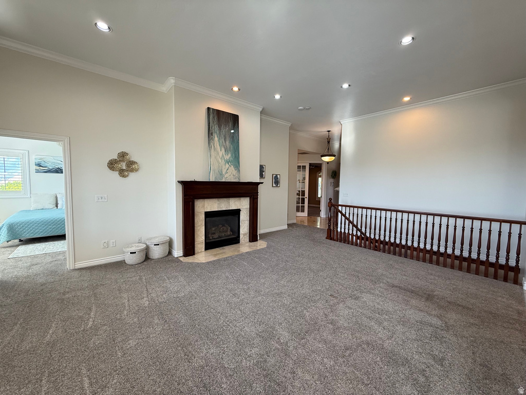 Living area featuring a dark wood mantel fireplace with a light tile surround, crown molding, recessed lighting, and grey carpet flooring