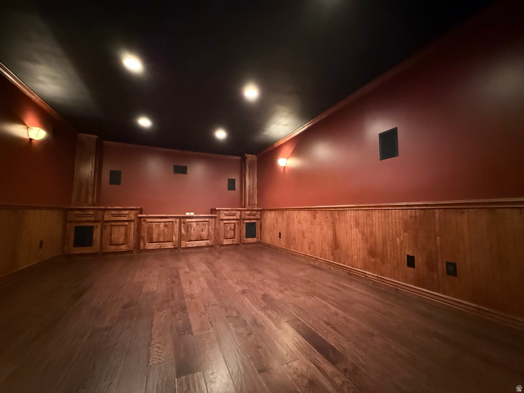Theater room featuring dark wood-finish flooring, recessed ceiling lighting, and built-in cabinetry with integrated speakers