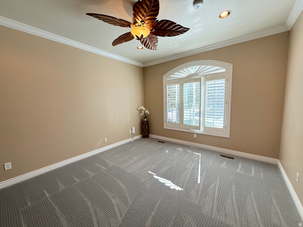 Room featuring an arched window with plantation shutters, crown molding, and a decorative ceiling fan