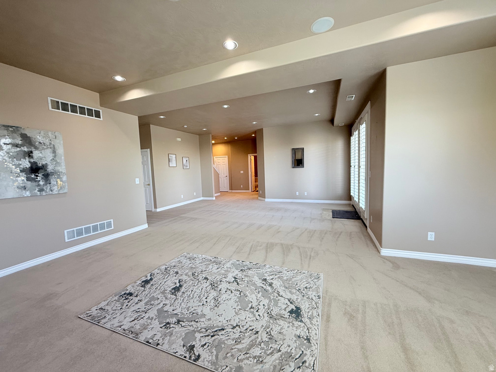 Spacious interior room with neutral-toned walls, recessed lighting, and light-colored carpet flooring