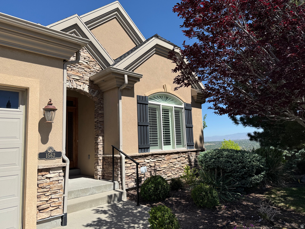 Stucco exterior with stone accents, featuring an arched entryway with a wooden door and a decorative sconce