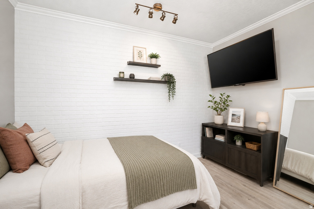 Bedroom featuring a white brick-finish accent wall, crown molding, and wood-finish flooring