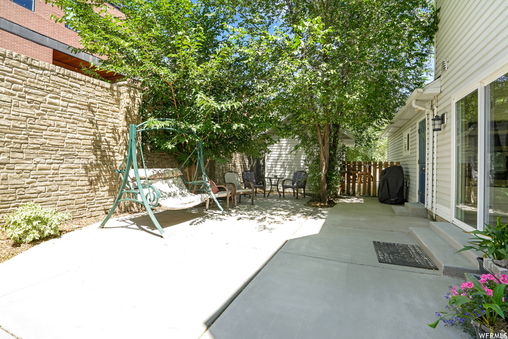 Private patio area featuring a textured stone privacy wall and mature trees