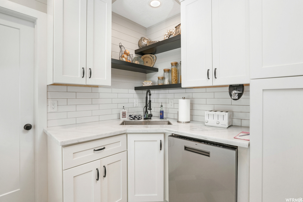 White shaker cabinetry with dark hardware, stone countertops, and a subway tile backsplash