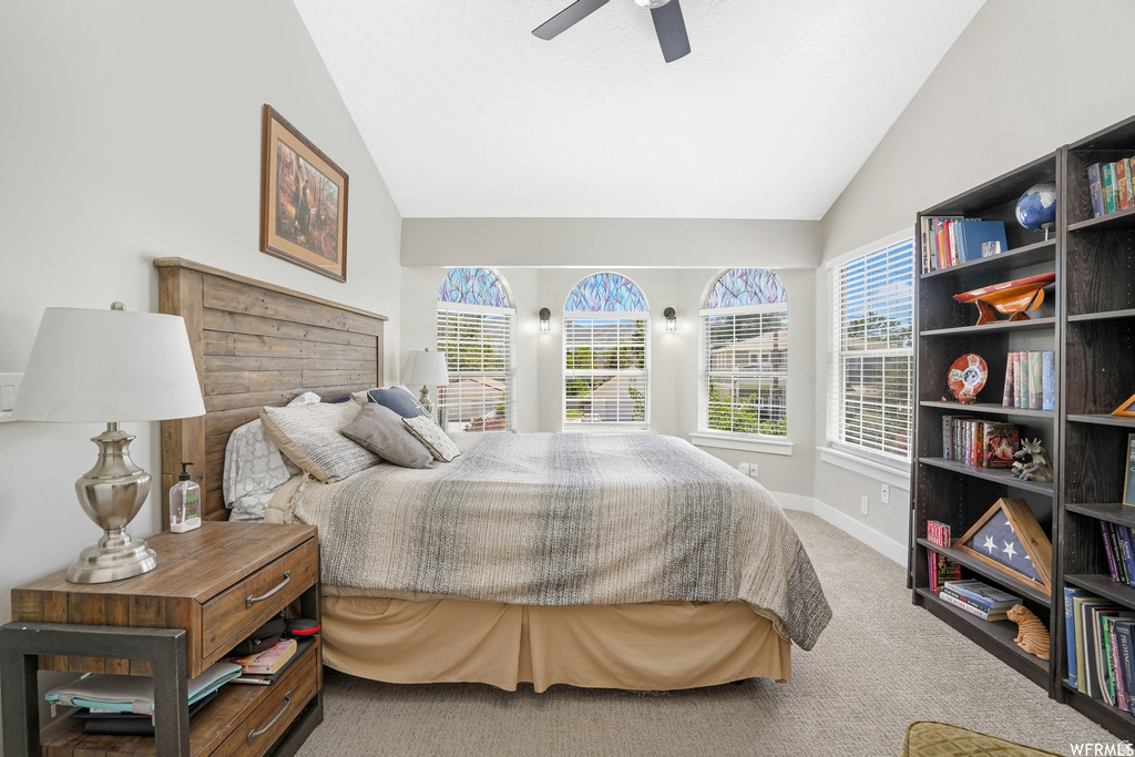 Vaulted ceiling room featuring a ceiling fan, three arched windows with blinds, a rectangular window with blinds, and built-in shelving