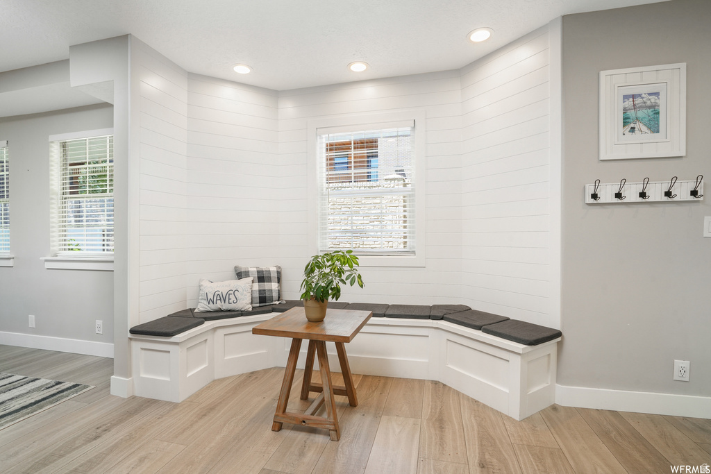 Built-in corner bench seating with storage, shiplap accent wall, recessed lighting, and wood-finish flooring