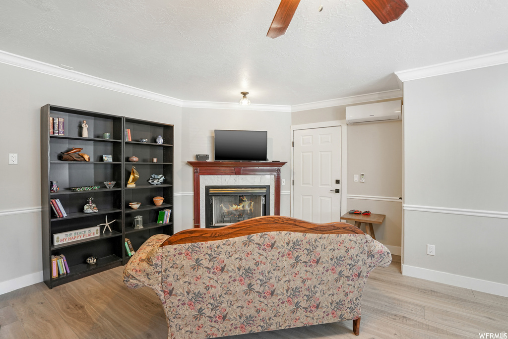 Living area featuring light wood-finish flooring and a corner fireplace with a dark wood mantel and a light-colored surround