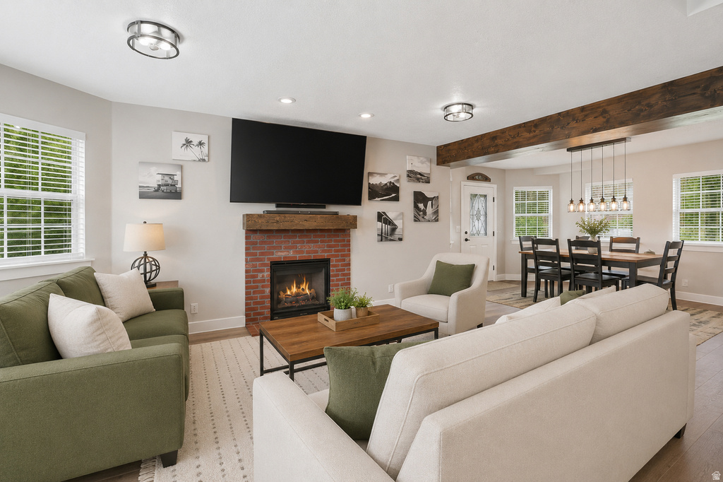 Living area featuring a brick fireplace with a wood-finish mantel, wood-finish flooring, and recessed lighting