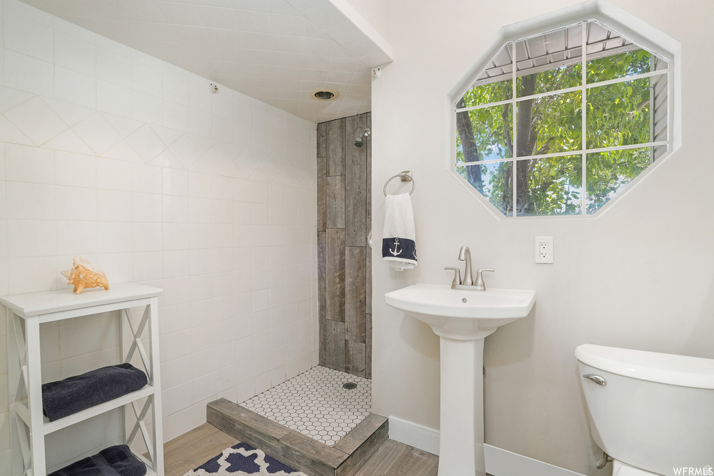 Bathroom featuring a pedestal sink, a toilet, and an octagonal window