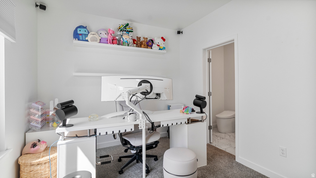 Room featuring neutral wall tones, carpet flooring, a built-in wall shelf, and a doorway to a bathroom with tile flooring and a toilet