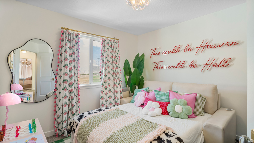 Bright bedroom featuring a double window with patterned curtains, a contemporary decorative mirror, and a ceiling-mounted light fixture