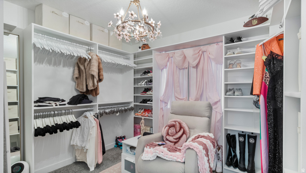 Spacious custom closet featuring extensive built-in shelving, multiple hanging rods, and an ornate chandelier