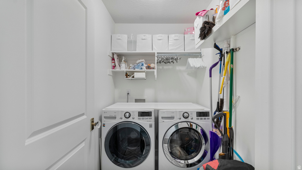 Dedicated laundry area featuring front-loading machines, built-in shelving, and a hanging rod