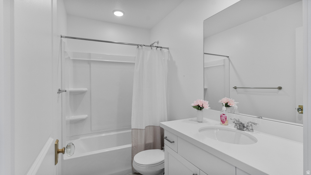 White bathroom featuring a single vanity with a white countertop and undermount sink, a large mirror, and a tub-shower combination with a white surround