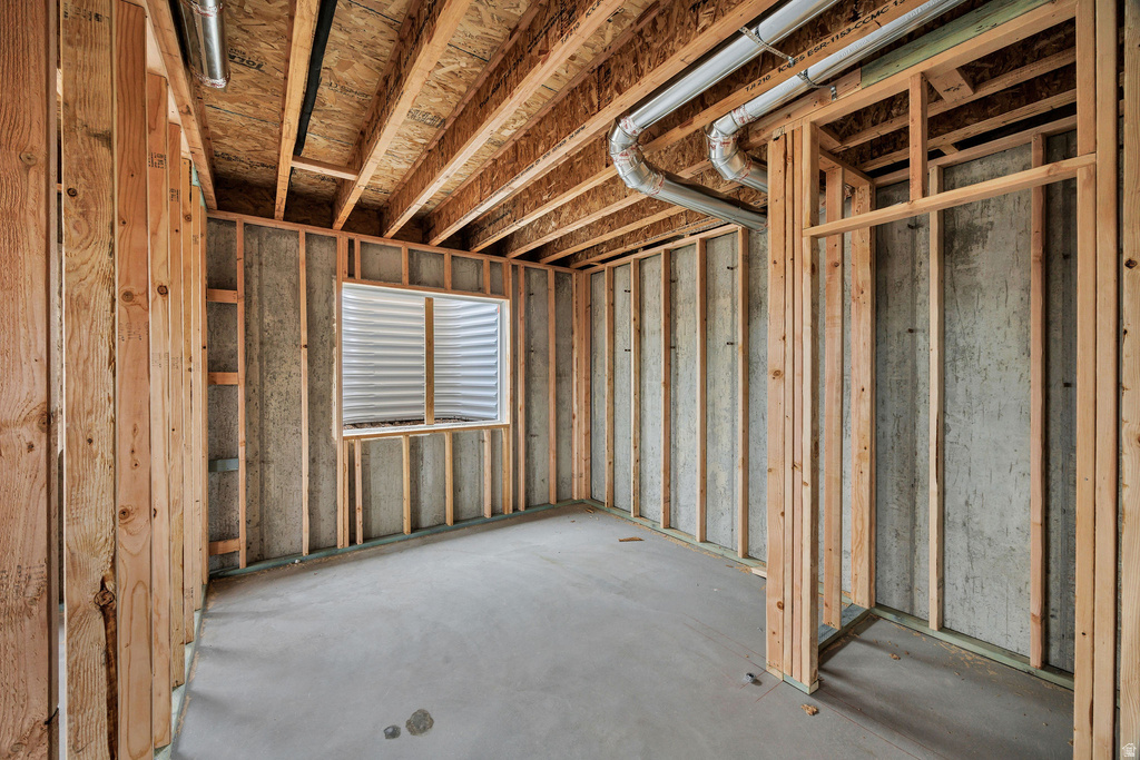 Unfinished basement space with exposed wood framing, concrete walls, and concrete flooring