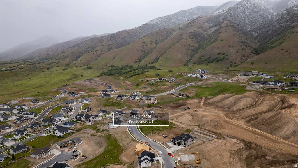 Developing residential area with established homes and new construction, set against a backdrop of rolling, green-covered mountains