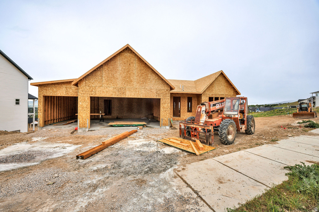 New construction property featuring a gable roofline, unfinished exterior sheathing, attached multi-car garage, and a concrete driveway