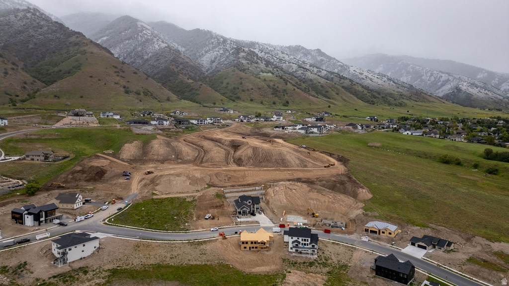 Hillside community featuring residential development, multiple new construction homes, paved roadways, and a mountainous backdrop