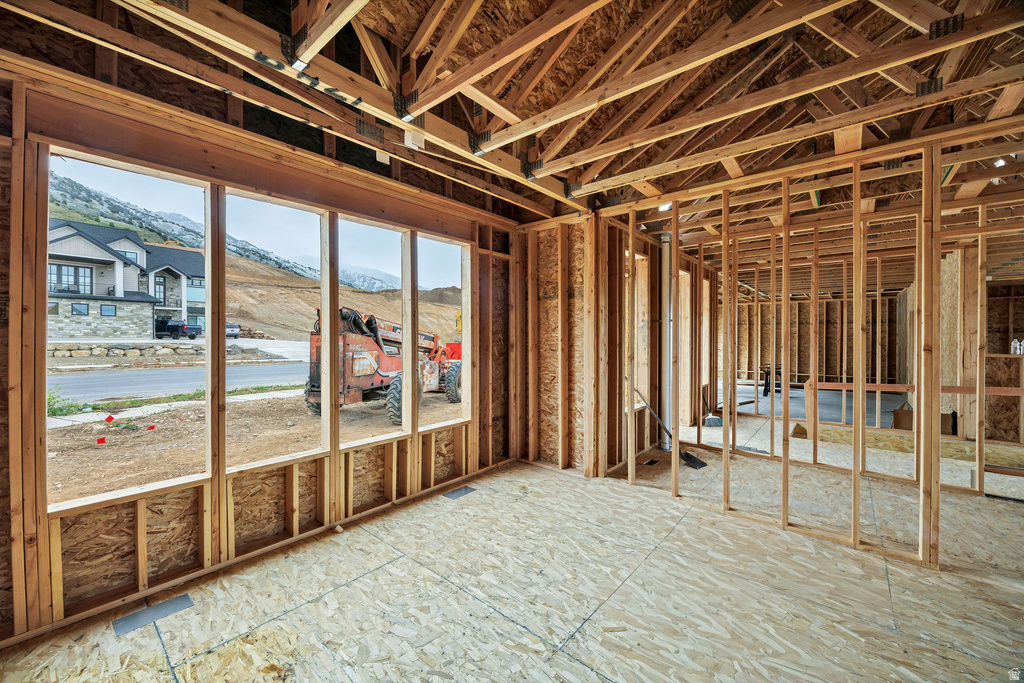 New construction framing featuring a spacious interior, large window openings, exposed wood trusses, and subfloor