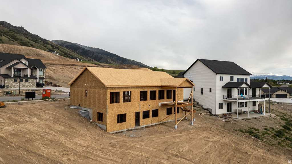 Under-construction residence featuring a wooden frame, multiple window openings, and an unfinished deck structure