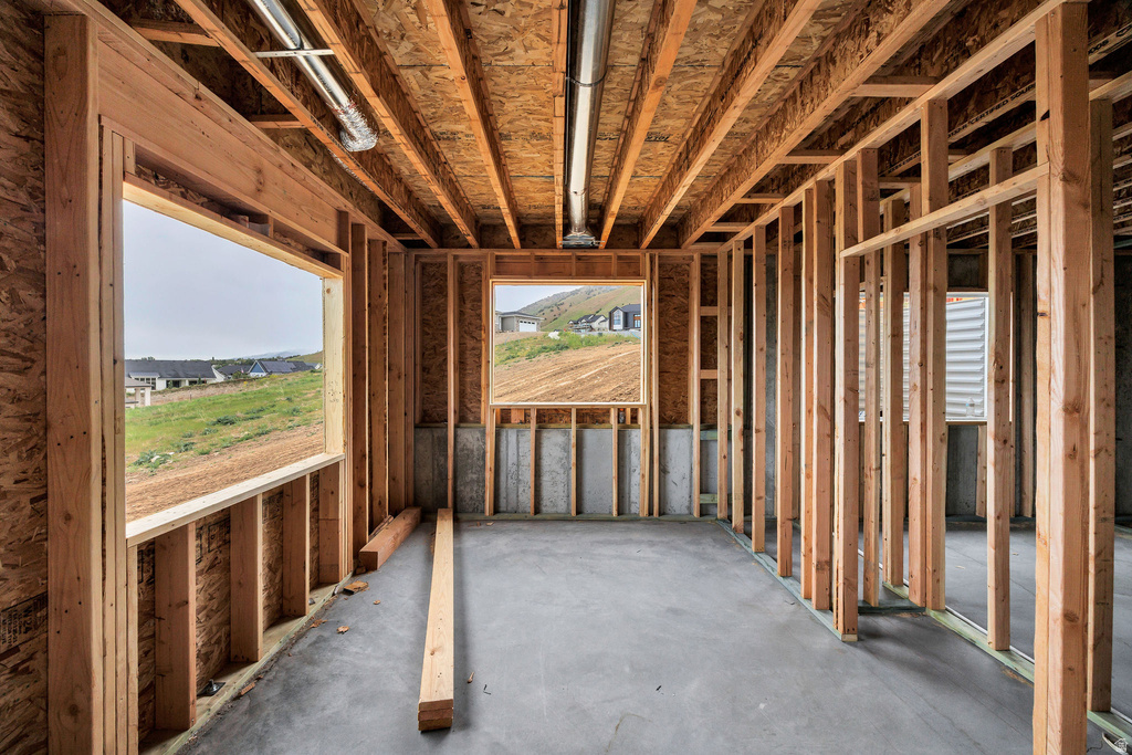 Unfinished interior space featuring exposed wood framing, concrete flooring, and visible ceiling joists
