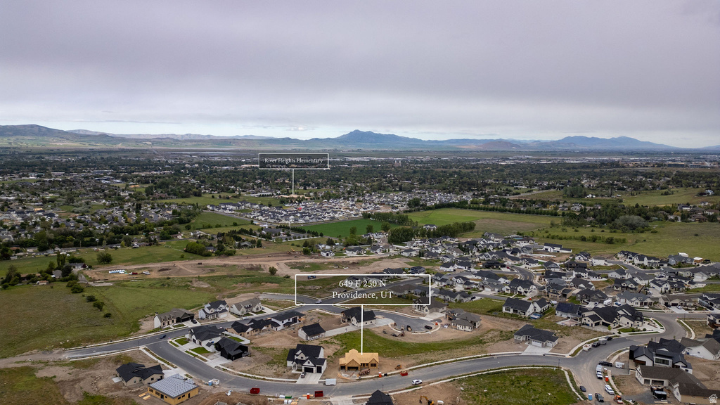 New construction community featuring a cul-de-sac street design and varied architectural styles, surrounded by green spaces and distant mountain ranges
