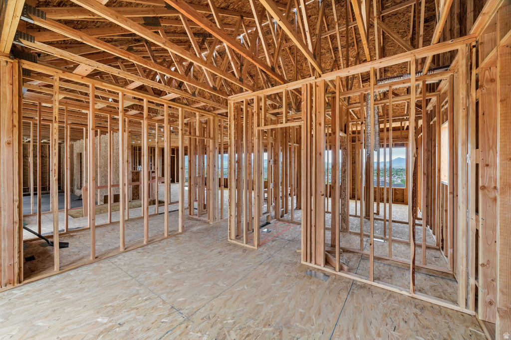 Interior framing showcasing structural wood elements, open ceiling trusses, plywood subflooring, and window openings