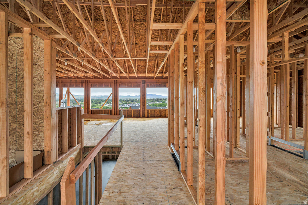 Unfinished interior framing revealing structural elements, multiple window openings, plywood subflooring, and exposed ceiling trusses