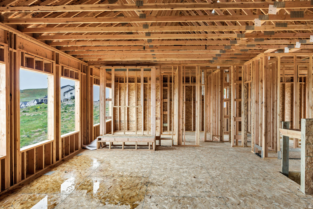 New construction framing featuring multiple window openings, engineered wood flooring, and exposed ceiling joists