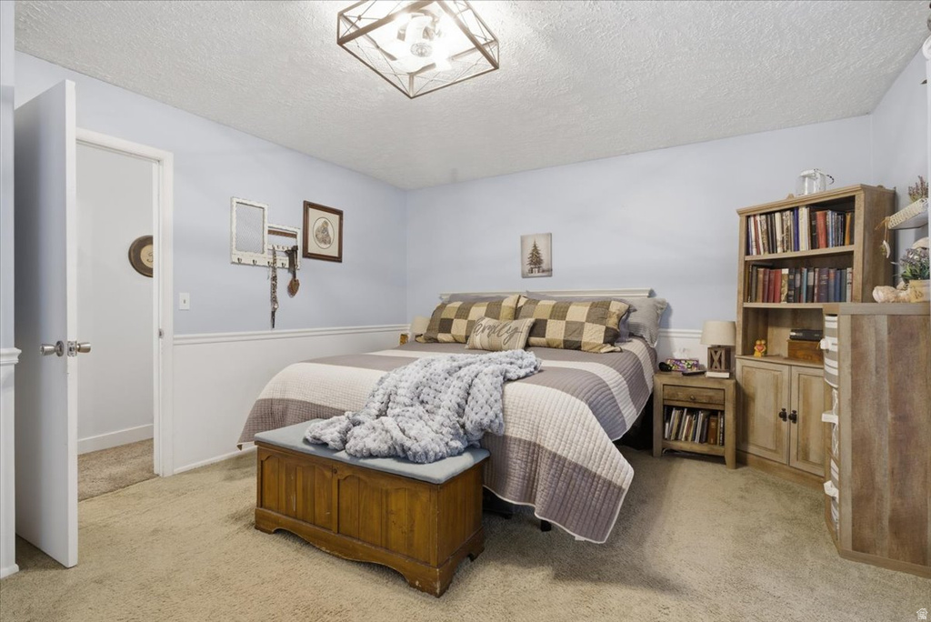 Bedroom featuring light blue walls, white wainscoting, and carpet flooring