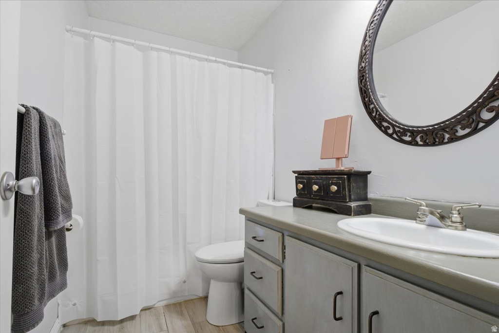 Vanity with integrated sink and brushed nickel faucet, ornate framed mirror, wood-finish flooring, and a white shower curtain with a white shower rod