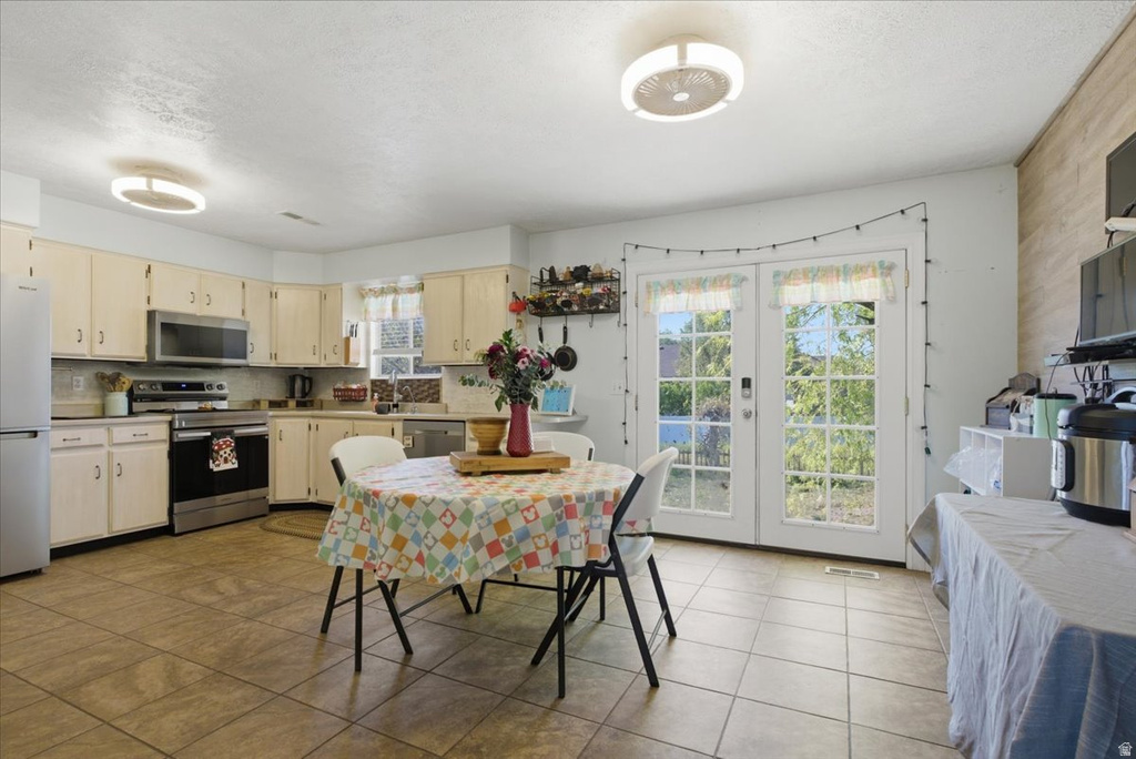 Kitchen featuring cream-colored cabinetry, stainless steel appliances, and a tile backsplash