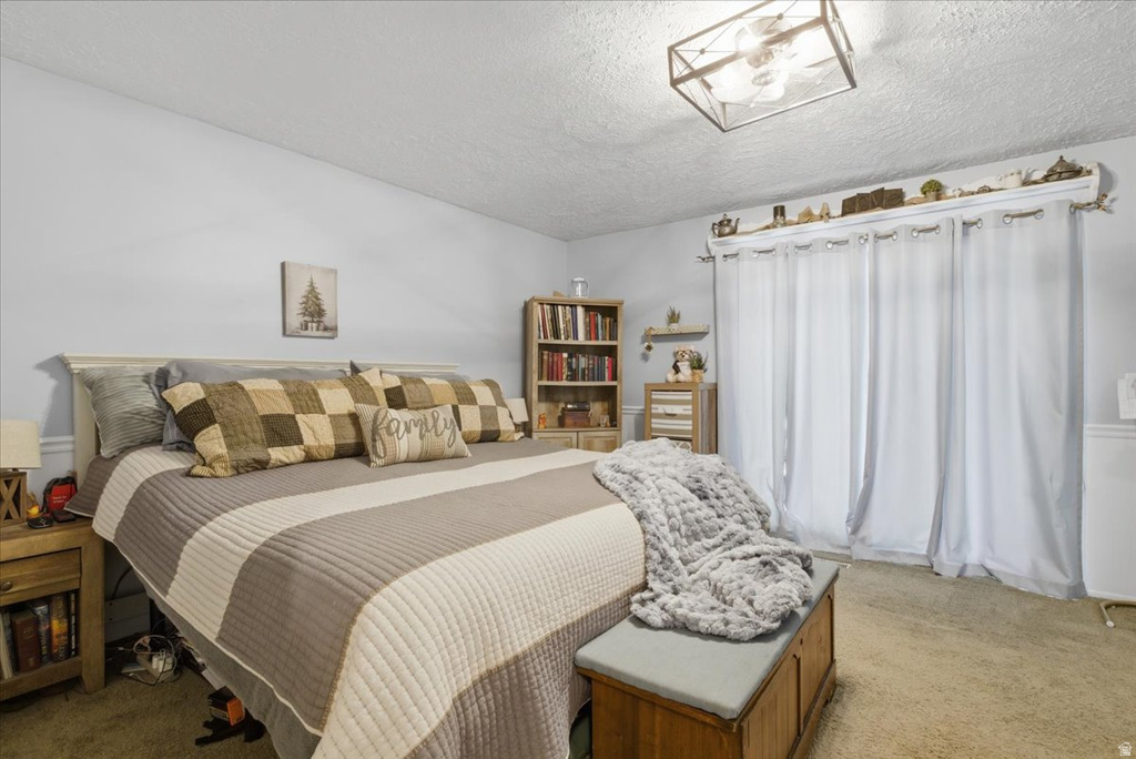 Carpeted bedroom featuring neutral wall tones, a ceiling-mounted light fixture, and a built-in shelf above the window treatment