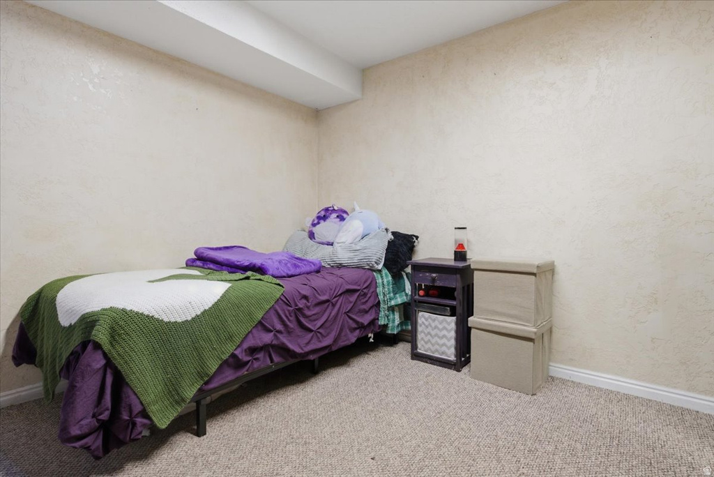 Carpeted room featuring textured neutral walls and a ceiling beam
