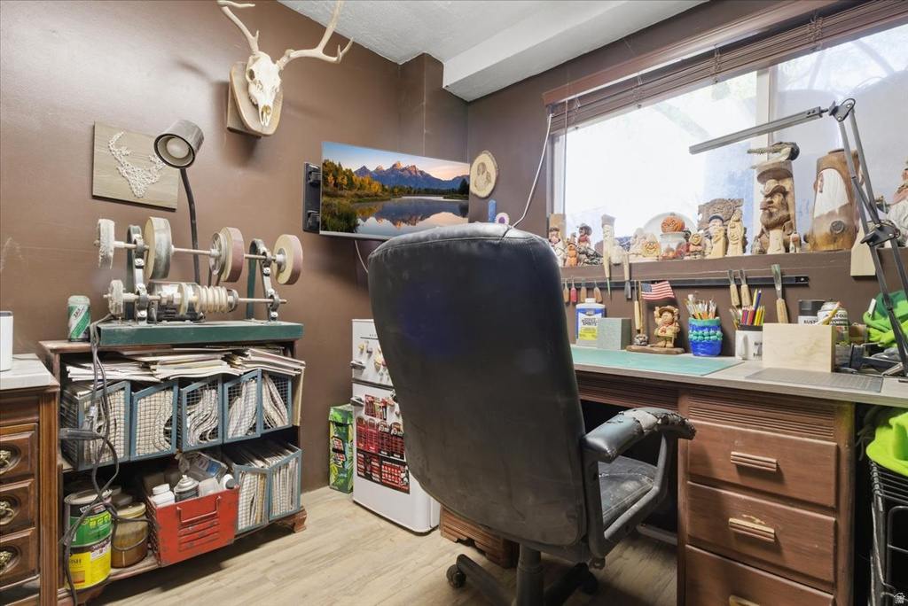 Dedicated workspace featuring wood-finish flooring and a substantial window with blinds
