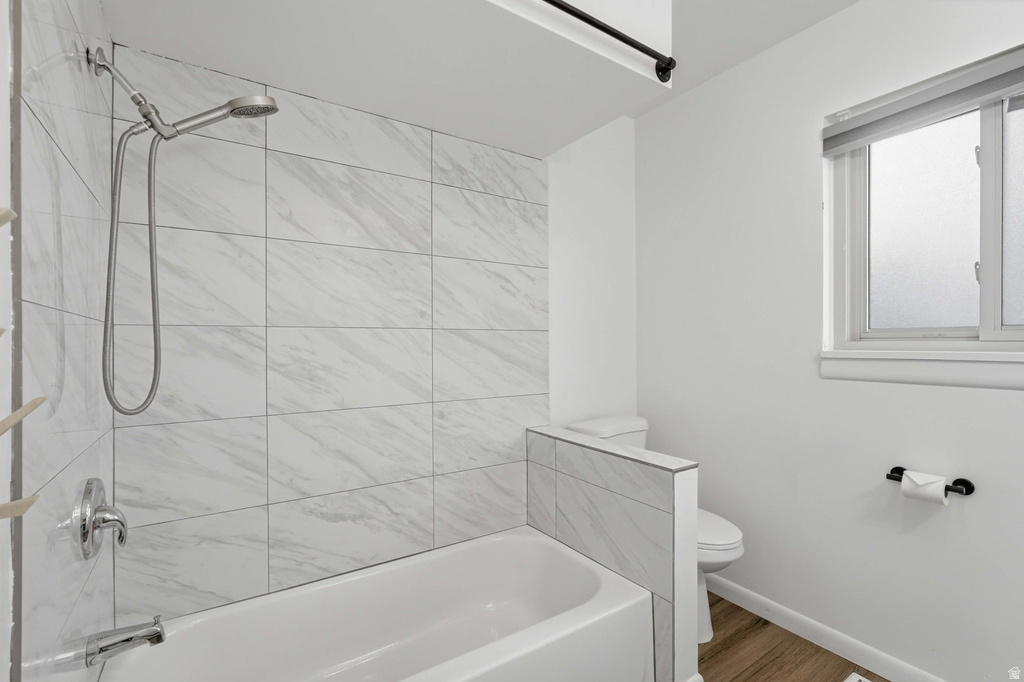 Bathtub and shower combination featuring white subway tile surround, brushed nickel fixtures, and a handheld showerhead