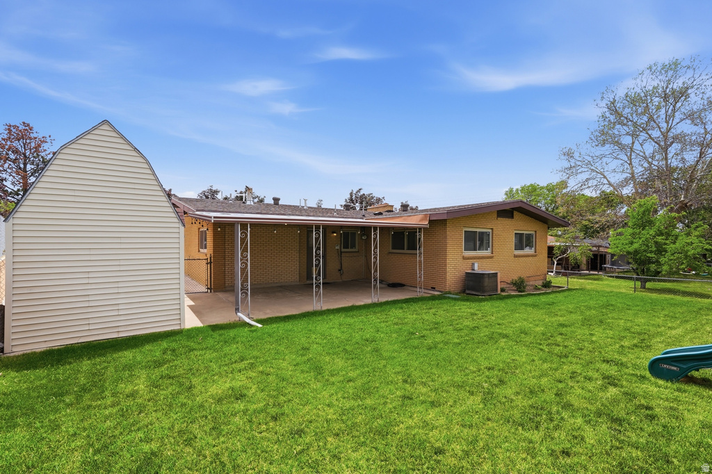 Expansive green lawn with a covered patio, featuring a brick-sided residence and an additional gabled structure