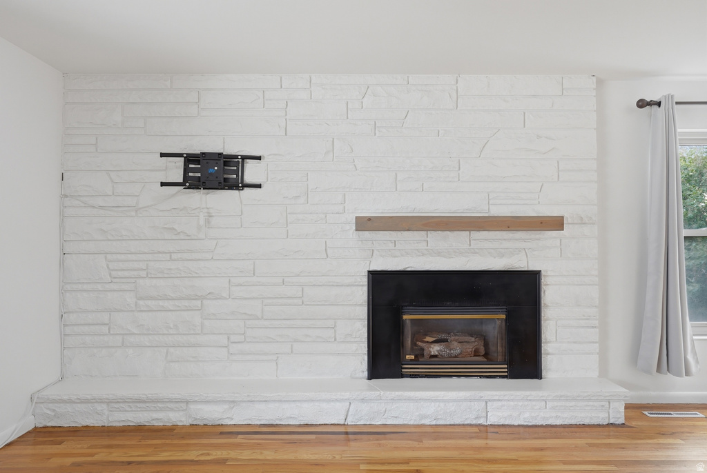 Stone-clad fireplace featuring a black firebox, a light wood mantle, and a raised hearth
