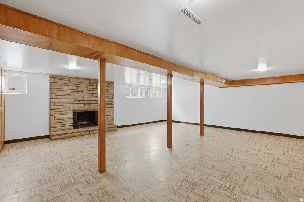 Spacious room with a stone fireplace, light-toned flooring, and wood-paneled support beams