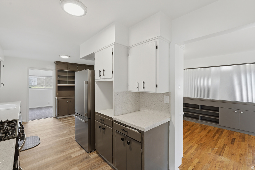 Kitchen featuring two-tone cabinetry, light-toned countertops, and wood-finish flooring