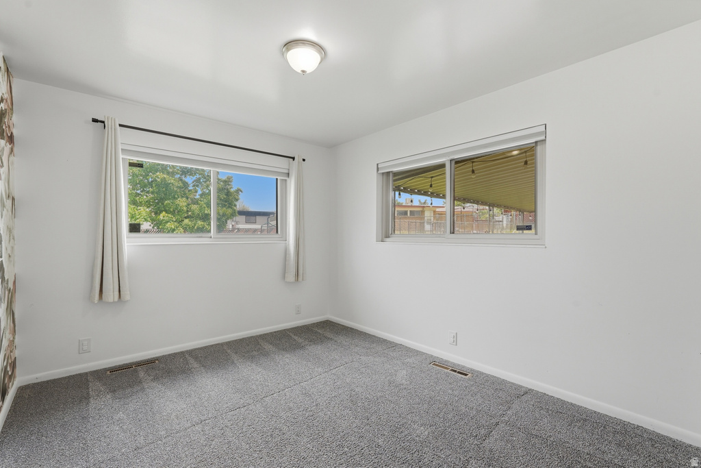 Room with light gray carpet, multiple windows, and a flush-mount ceiling light