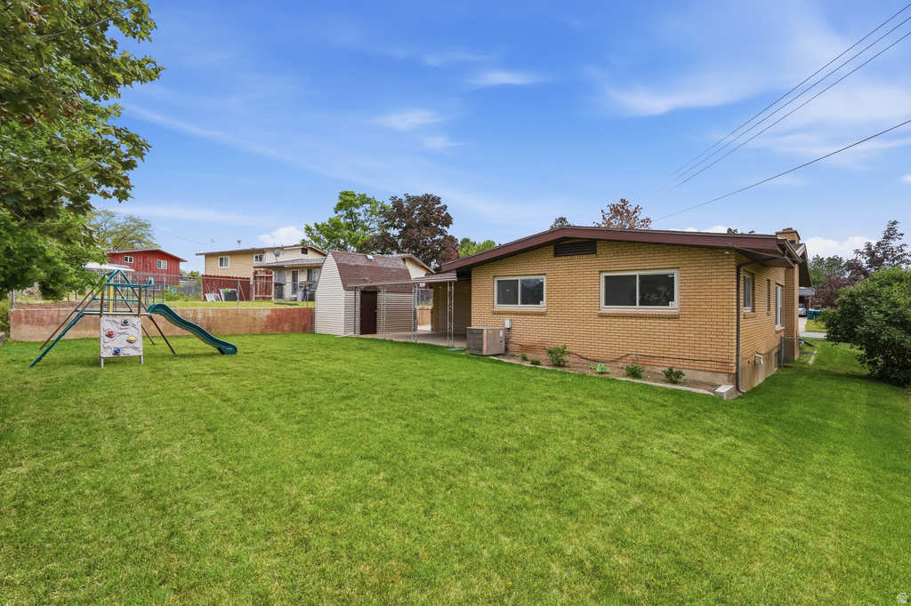 Spacious backyard featuring a manicured lawn, a detached storage shed, and a brick exterior with multiple windows