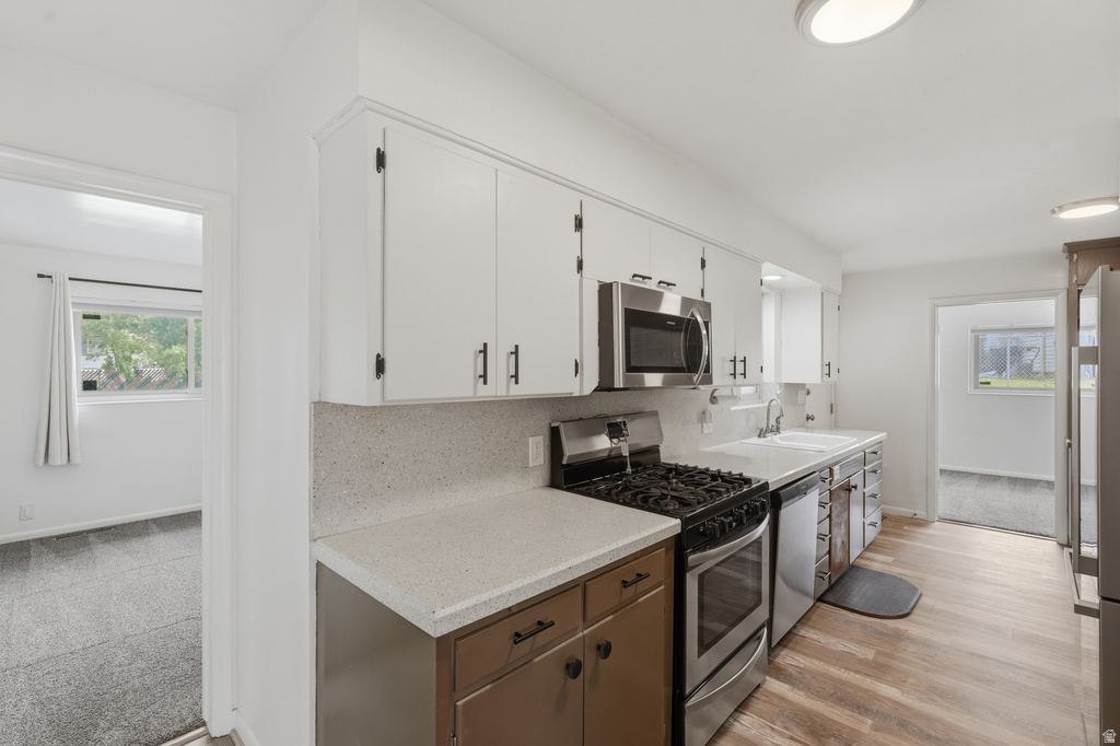 Kitchen featuring white upper cabinetry, two-tone lower cabinetry, and light-toned countertops