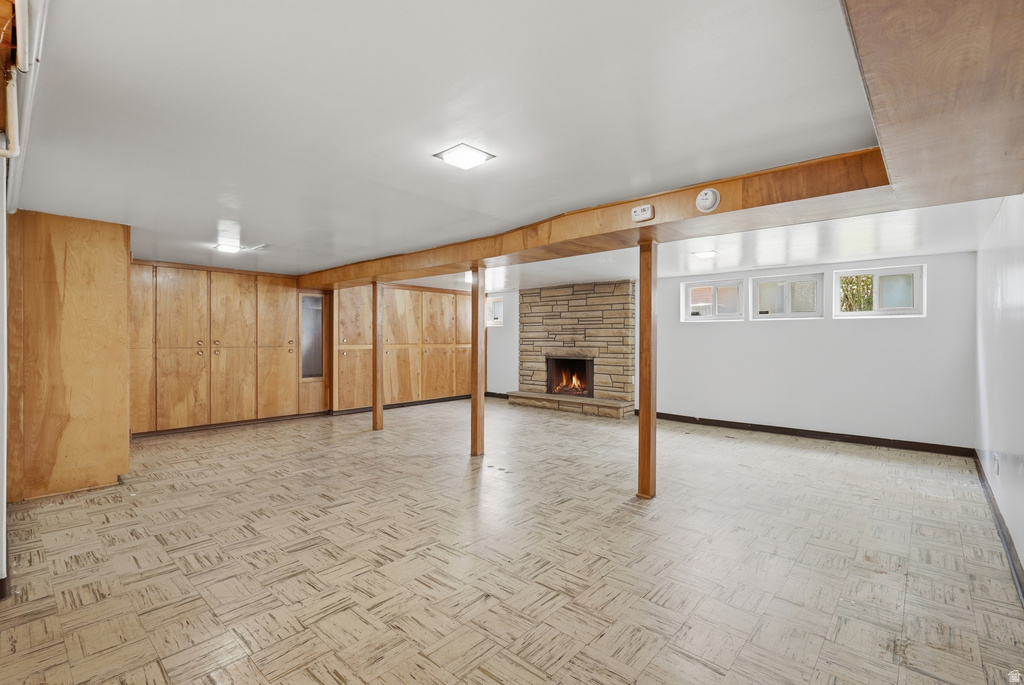 Spacious lower-level room featuring extensive built-in wood cabinetry, a stone fireplace, patterned floor tiles, recessed lighting, and multiple transom windows