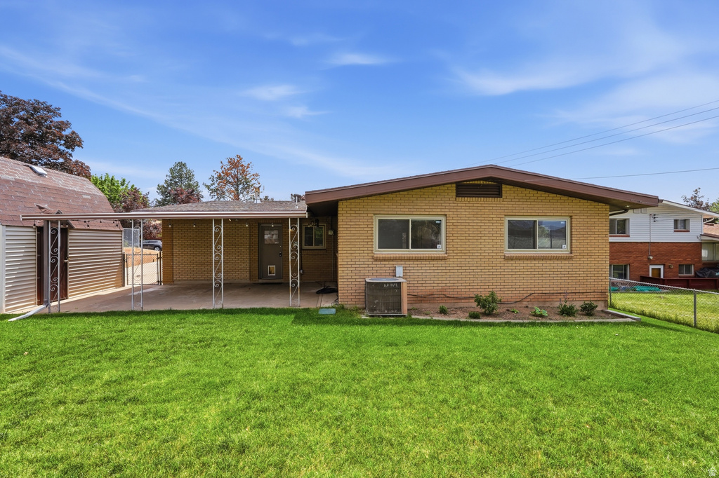 Spacious backyard with a covered patio, featuring a manicured lawn, brick exterior, and an additional storage shed